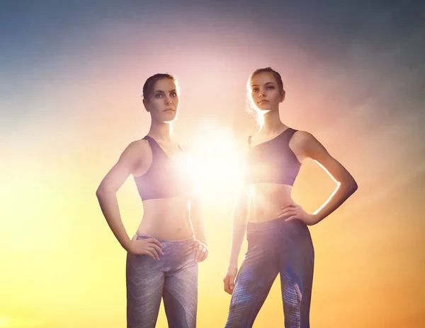 Duas meninas de esportes no fundo por do sol . — Fotografia de Stock