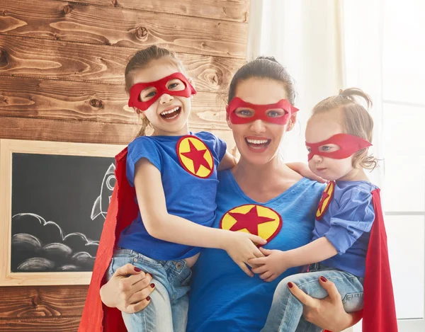 Meisjes en mama in superheld kostuums — Stockfoto