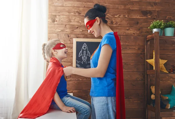 Meisje en moeder in een superheld kostuum — Stockfoto