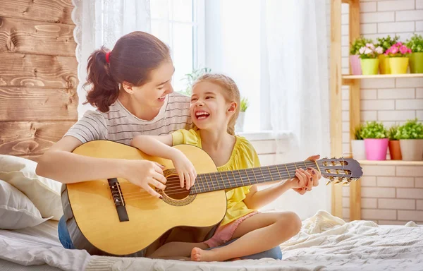 Kobieta gra na gitarze za dziecko dziewczynka — Zdjęcie stockowe