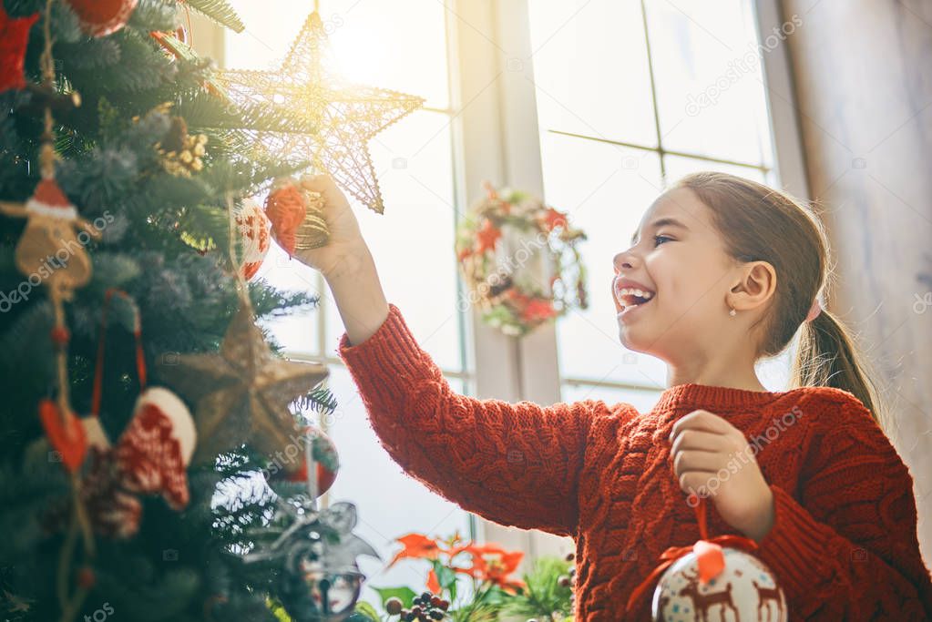 girl is decorating Christmas tree