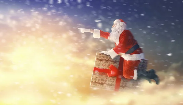 Weihnachtsmann fliegt auf Geschenkbox — Stockfoto