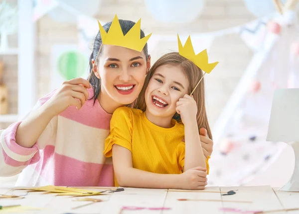 Mor och dotter med kronor papper — Stockfoto