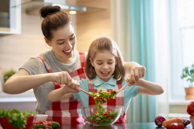 Evde sağlıklı yemek. Mutfakta mutlu bir aile. Anne ve çocuk kızı sebze hazırlama.
