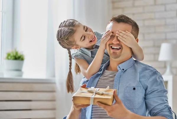 Happy father's day! Child daughter congratulating dad and giving him gift box. Daddy and girl smiling and hugging. Family holiday and togetherness.
