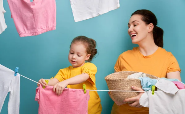 Mujer y niña colgando ropa en una cuerda — Foto de Stock