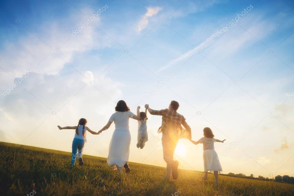 Happy family on summer walk! Mother, father and daughters walking in the Park and enjoying the beautiful nature.