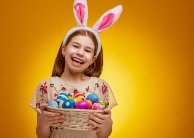 Paskalya günü tavşan kulağı takan şirin bir çocuk. Sarı arka plandaki kız.                                  