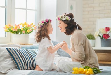 Anneler Günün kutlu olsun! Çocuk annesini tebrik ediyor. Anne ve kızı gülümsüyor ve sarılıyorlar. Aile tatili ve birliktelik.                                                              