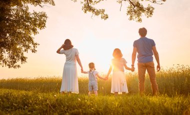 Yaz yürüyüşündeki mutlu aile! Anne, baba ve kızlar parkta yürüyor ve güzel doğanın tadını çıkarıyorlar..