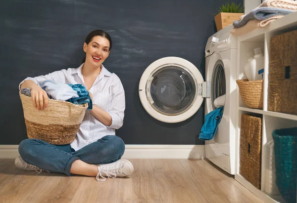美しい若い女性は家で洗濯をしながら笑っています — ストック写真