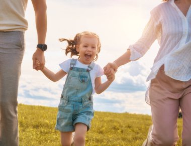 Yaz yürüyüşündeki mutlu aile! Anne, baba ve kızlar parkta yürüyor ve güzel doğanın tadını çıkarıyorlar..                                                              