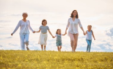 Yaz yürüyüşündeki mutlu aile! Anne, büyükanne ve kızları parkta yürüyor ve güzel doğanın tadını çıkarıyorlar..