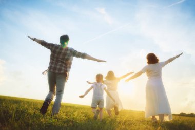 Yaz yürüyüşündeki mutlu aile! Anne, baba ve kızlar parkta yürüyor ve güzel doğanın tadını çıkarıyorlar..  