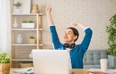 Evde dizüstü bilgisayarda çalışan mutlu ve güzel bir kadın..