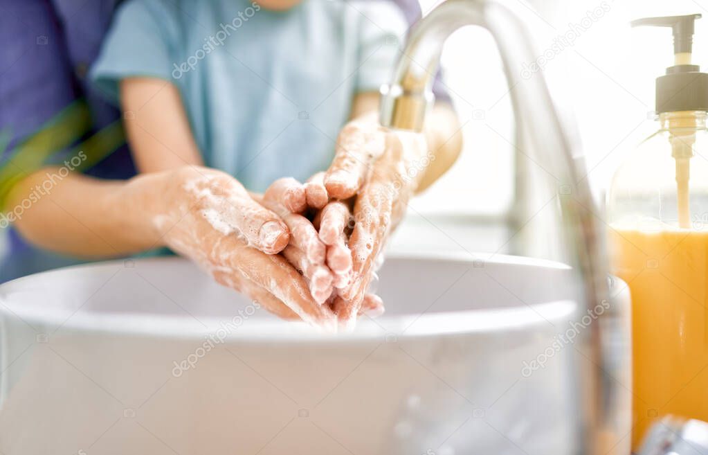 Kid and adult are washing their hands. Protection against infections and viruses. Close up.                                  