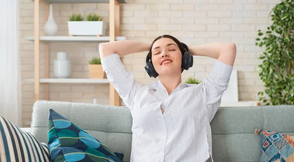 Neşeli Genç Bir Kadın Kulaklıkla Müzik Dinliyor Evdeki Kanepede Oturuyor — Stok fotoğraf