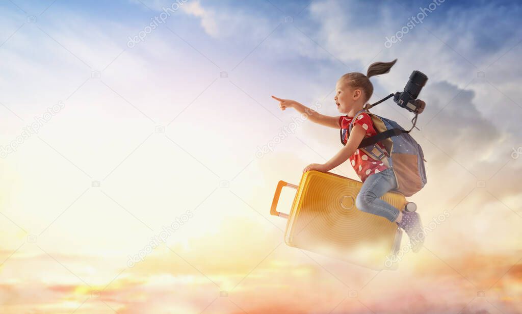 Dreams of travel! Child flying on a suitcase against the backdrop of sunset.                               