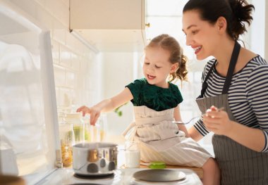 Evde sağlıklı yiyecekler. Mutfakta mutlu bir aile. Anne ve kız doğru düzgün bir yemek hazırlıyorlar.. 