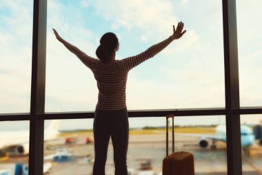 Maceraya çık! Genç ve güzel bir kadın havaalanında bir uçağa bakıyor..