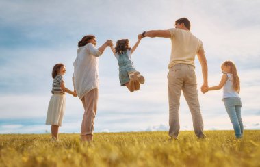 Yaz yürüyüşündeki mutlu aile! Anne, baba ve kızlar parkta yürüyor ve güzel doğanın tadını çıkarıyorlar..