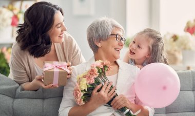Anneler Günün kutlu olsun! Çocuk kızı, anne ve büyükannenin onlara çiçek ve hediye vermesini kutluyor. Büyükanne, anne ve kız gülümsüyor ve sarılıyorlar. Aile tatili ve birliktelik. 