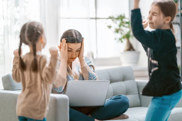 ノートパソコンで働く女性 騒々しい子供たちと家からのリモートワーク — ストック写真