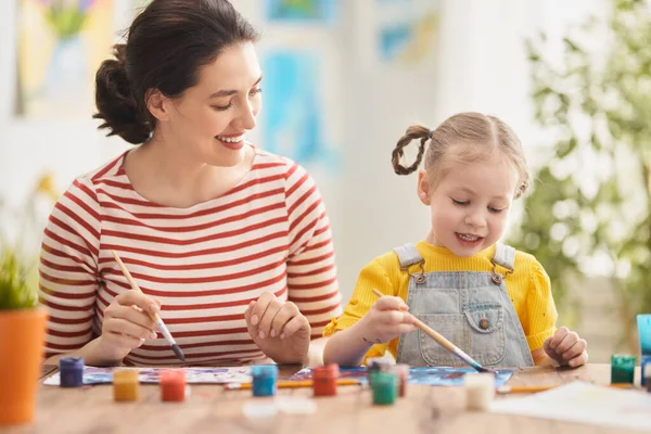 幸せな家族だ 母と娘が一緒に絵を描く 子供の女の子を助ける大人の女性 — ストック写真