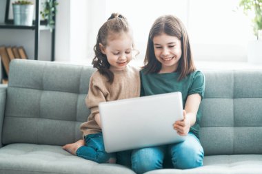 Sevgi dolu bir aile. Dizüstü bilgisayar kullanan çocuklar. Komik kızlar evde kalarak eğleniyorlar..                                 