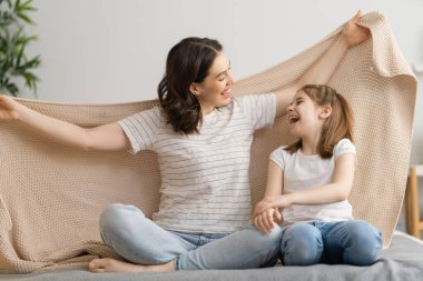 Hoş bir kız ve annesi güneşli bir sabahın tadını çıkarırlar. Evde iyi eğlenceler. Çocuk uykudan uyanıyor. Aile yatak odasındaki yatakta battaniyenin altında oynuyor..