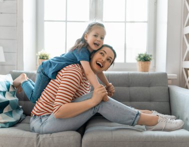 Anneler Günün kutlu olsun! Anne ve kızı oynuyorlar, gülümsüyorlar ve sarılıyorlar. Aile tatili ve birliktelik.      