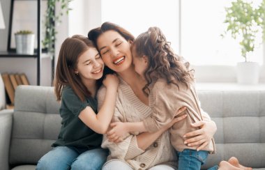 Anneler Günün kutlu olsun! Anne ve kızları oynuyorlar, gülüyorlar ve sarılıyorlar. Aile tatili ve birliktelik.     