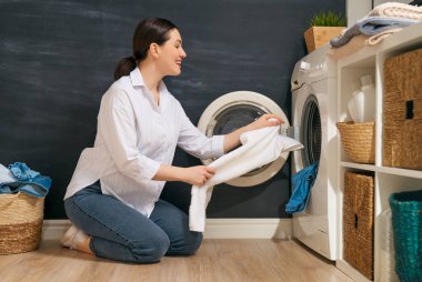 Güzel genç bayan evde çamaşır yıkarken gülümsüyor..                                 