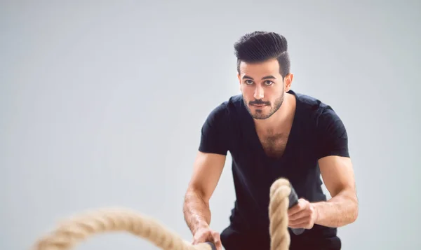 Atlético Joven Haciendo Ejercicios Crossfit Con Una Cuerda Sobre Fondo — Foto de Stock