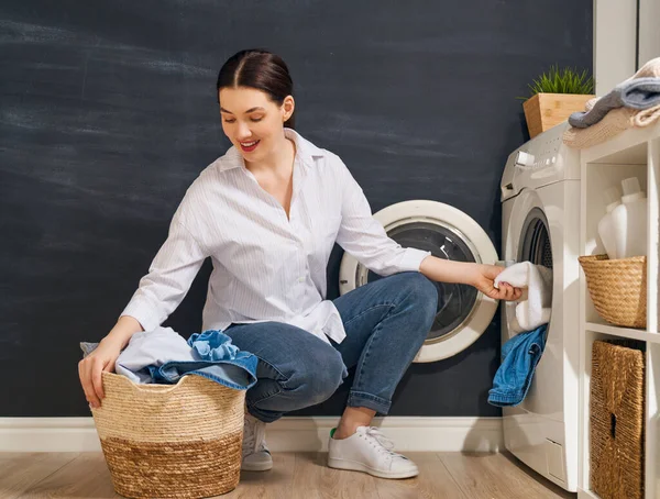 美しい若い女性は家で洗濯をしながら笑っています — ストック写真