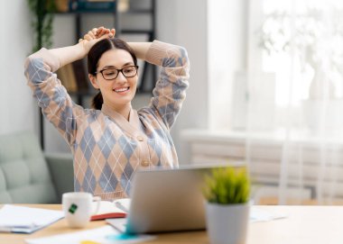 Evde dizüstü bilgisayarda çalışan mutlu ve güzel bir kadın..