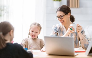 Bilgisayarda çalışan çocuklu genç bir anne. Aile evde. Uzak çalışma.  