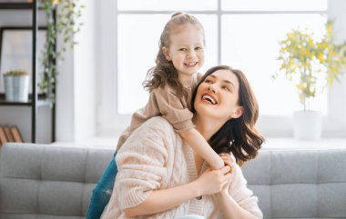 Anneler Günün kutlu olsun! Anne ve kızı oynuyorlar, gülümsüyorlar ve sarılıyorlar. Aile tatili ve birliktelik.  