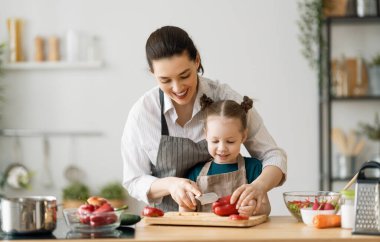 Evde sağlıklı yiyecekler. Mutfakta mutlu bir aile. Anne ve kız doğru düzgün bir yemek hazırlıyorlar..