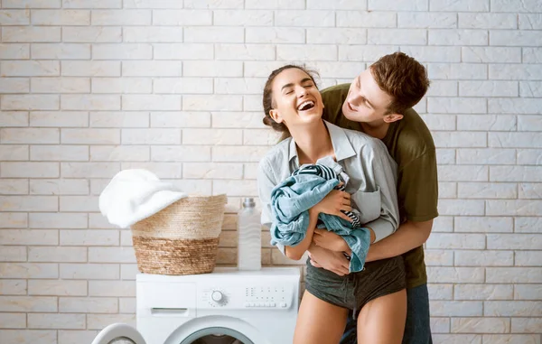 美しい若い愛情のカップルは家で洗濯をしながら笑っています — ストック写真
