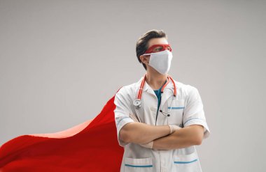 Koronavirüs salgını sırasında maskeli ve süper kahraman pelerinli bir doktor. Virüs ve hastalık koruması, karantina. COVID-2019. Tıbbın süper kahraman gücü..