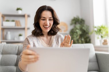 Genç bayan arkadaşlarıyla uzaktan konuşmak için bilgisayarını kullanıyor. Komik kız evde kalıp eğleniyor..