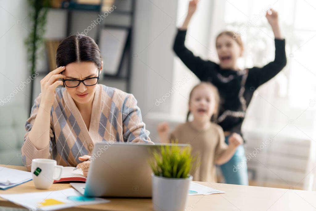 Woman working on a laptop. Noisy children and remote work from home. 