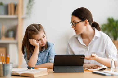 Okula dönelim. Mutsuz çocuk ve yetişkin masada oturuyor. Ödev yapan ya da online eğitim alan kız.