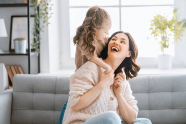 Mutlu bir gün! Anne ve kızı oynuyorlar, gülümsüyorlar ve sarılıyorlar. Aile tatili ve birliktelik. 