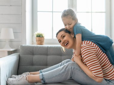 Mutlu bir gün! Anne ve kızı oynuyorlar, gülümsüyorlar ve sarılıyorlar. Aile tatili ve birliktelik. 