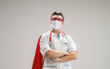 Koronavirüs salgını sırasında maskeli ve süper kahraman pelerinli bir doktor. Virüs ve hastalık koruması, karantina. COVID-2019. Tıbbın süper kahraman gücü..
