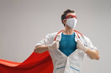 Koronavirüs salgını sırasında maskeli ve süper kahraman pelerinli bir doktor. Virüs ve hastalık koruması, karantina. COVID-2019. Tıbbın süper kahraman gücü..