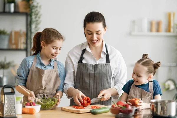 Healthy food at home. Happy family in the kitchen. Mother and children daughters are preparing vegetables.