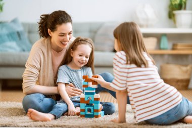 Mutlu bir gün! Anne ve kızları oynuyorlar, gülüyorlar ve sarılıyorlar. Aile tatili ve birliktelik. 